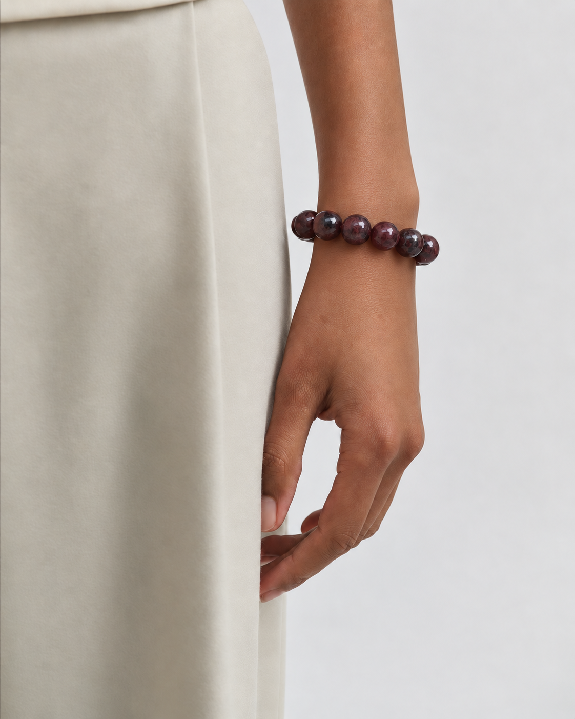 Chunky Garnet bracelet worn on the wrist, styled with a cream skirt