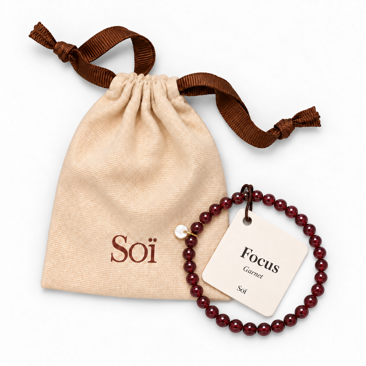 Garnet bracelet with its Focus meaning card, resting on a Soï linen gift pouch with a brown ribbon