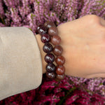 Chunky Garnet bracelet stacked with a second garnet bracelet on the wrist against purple heather