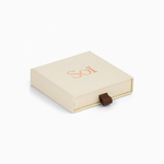 Medium Soï jewelry box in cream with a rose-gold foil logo and brown ribbon pull, the gift box this piece ships in