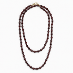 Lea Garnet necklace laid out double, showing its long strand of dark red natural stone beads