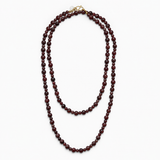 Lea Garnet necklace laid out double, showing its long strand of dark red natural stone beads